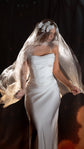 Bride lifting the edges of an organza wedding veil with a lace crown, the fabric floating around a satin slip gown, ethereal, Vespera