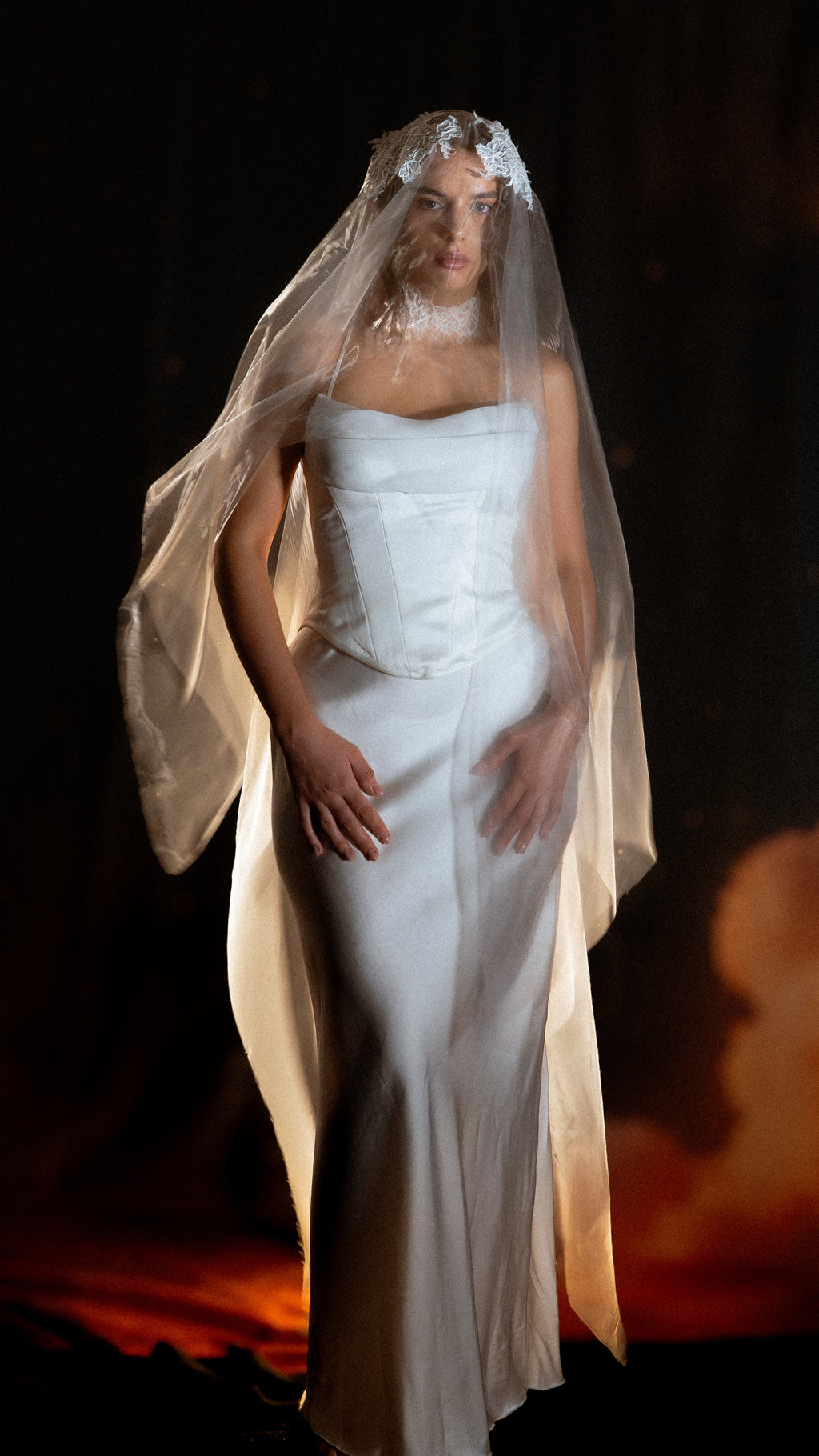 Front view of a bride under a sheer wedding veil with a Chantilly lace crown, organza falling past the hips, warm glow behind, Vespera