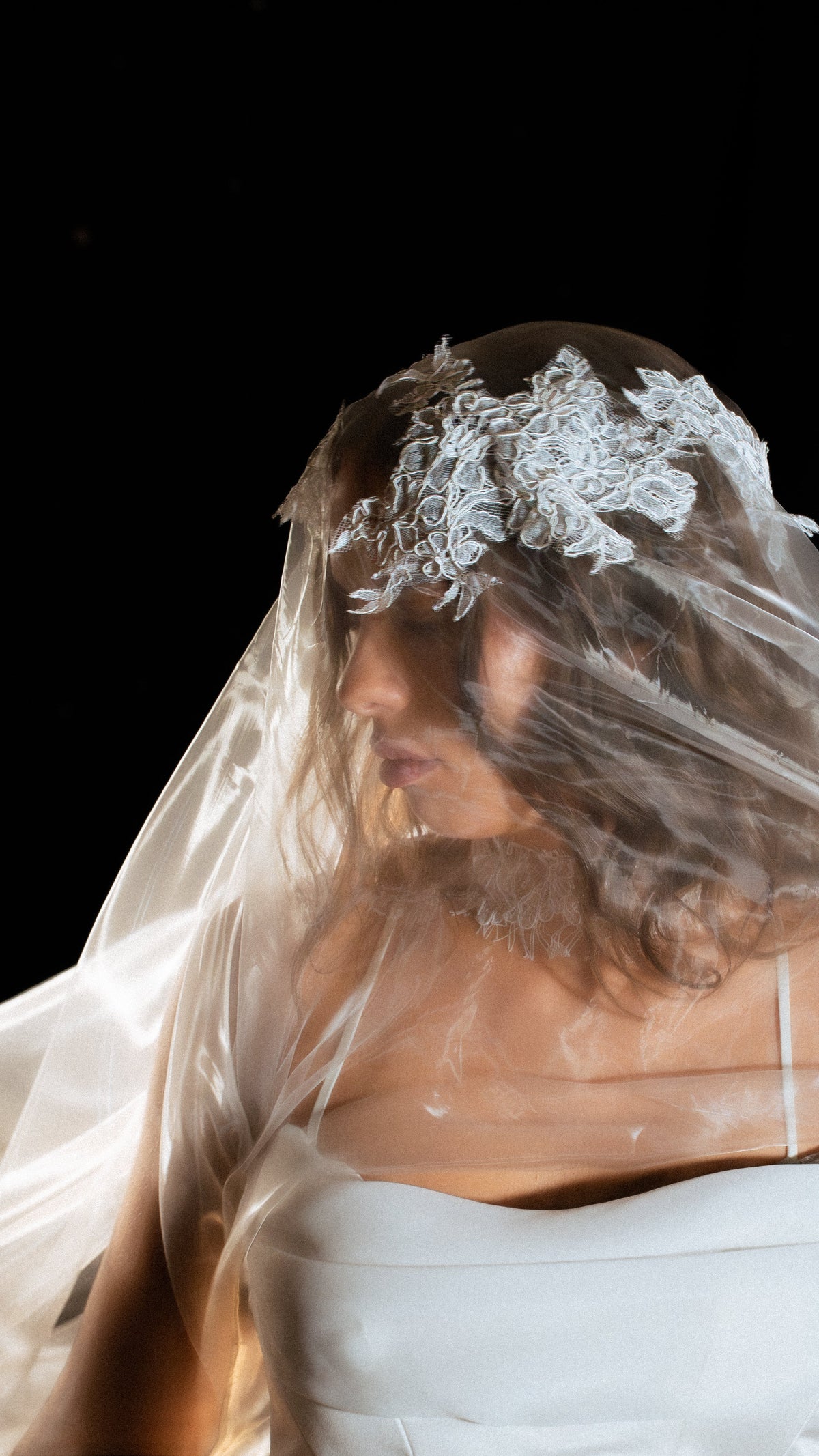 Close crop of the Chantilly lace crown on an organza wedding veil, sheer fabric drifting across the face, Vespera