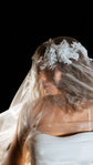Close crop of the Chantilly lace crown on an organza wedding veil, sheer fabric drifting across the face, Vespera