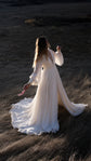 Chiffon sample wedding dress with sheer long sleeves, slit and train, bride in a dark meadow holding flowers, When the Moon is Out Sample by Ephemeris