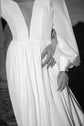 Black and white crop of a plunging V neckline chiffon sample wedding dress with a gathered waist, groom's hand at her hip, When the Moon is Out Sample