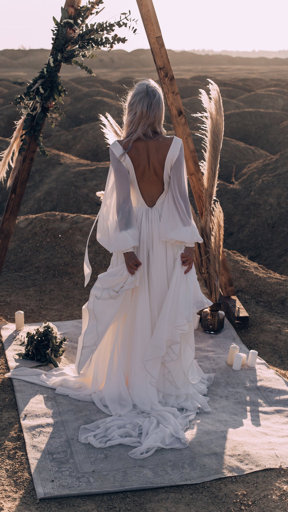 Back view of an A-line chiffon sample wedding dress with long sleeves and a deep open back under a wooden arch, When the Moon is Out Sample