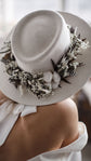 Close detail of the neck tie at the back of a chiffon wedding dress under a felt hat, bare shoulder in soft light, When the Moon is Out