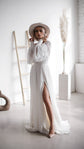 Bride with hands at her hat in a chiffon wedding dress with puffed sleeves and a high slit, pampas grass behind, When the Moon is Out