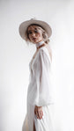 Bride in profile with a chiffon scarf at the neck, sheer balloon sleeve of an A-line wedding dress, bright window light, When the Moon is Out