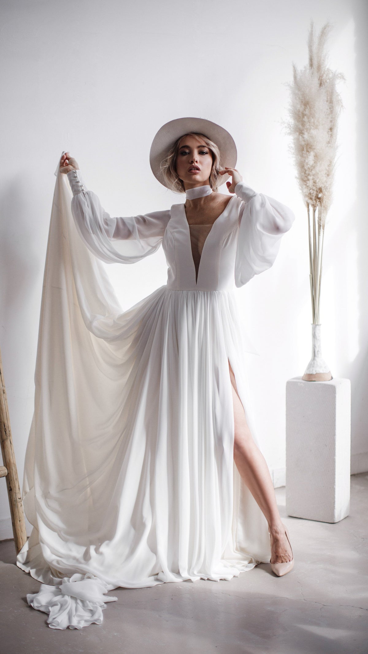 Bride holding the back scarf out wide in a plunging chiffon wedding dress with a slit, pampas in a vase, When the Moon is Out