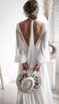 Back view of a chiffon wedding dress with a deep V back and the scarf trailing down the spine, bride holding a hat, When the Moon is Out