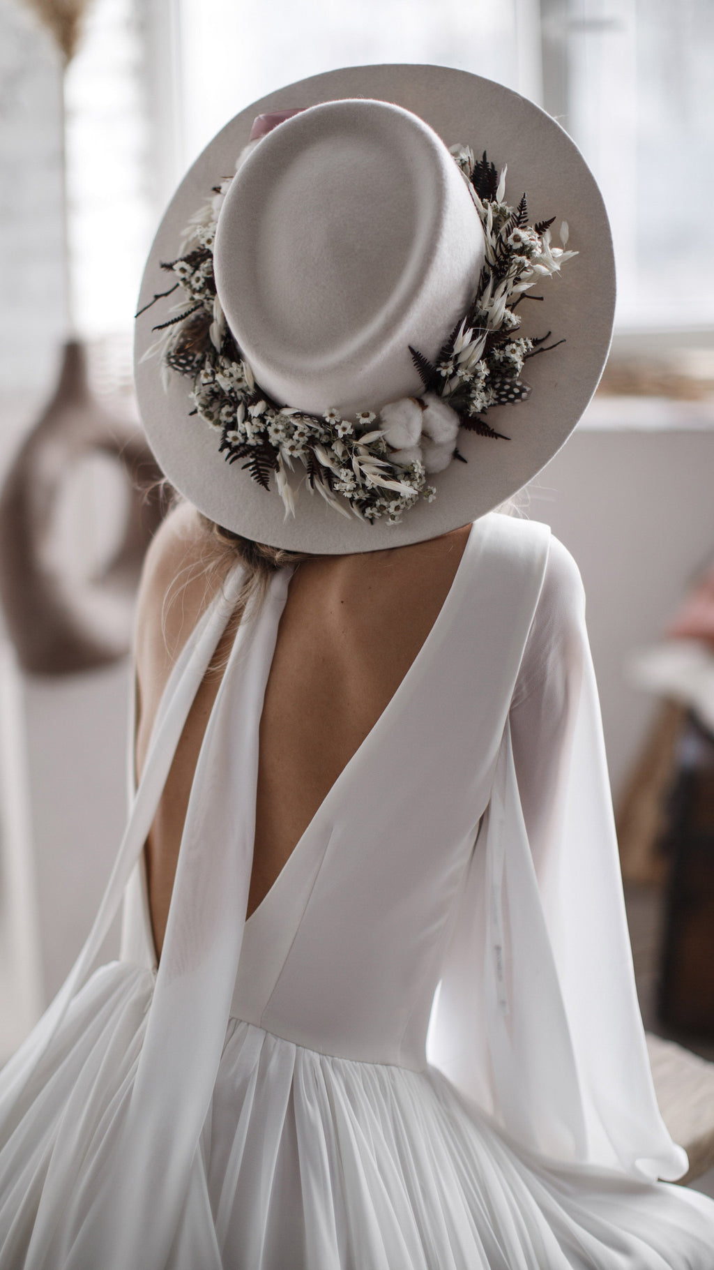Overhead crop of a flower-trimmed hat and the deep V back of a chiffon wedding dress with the scarf tied at the neck, When the Moon is Out