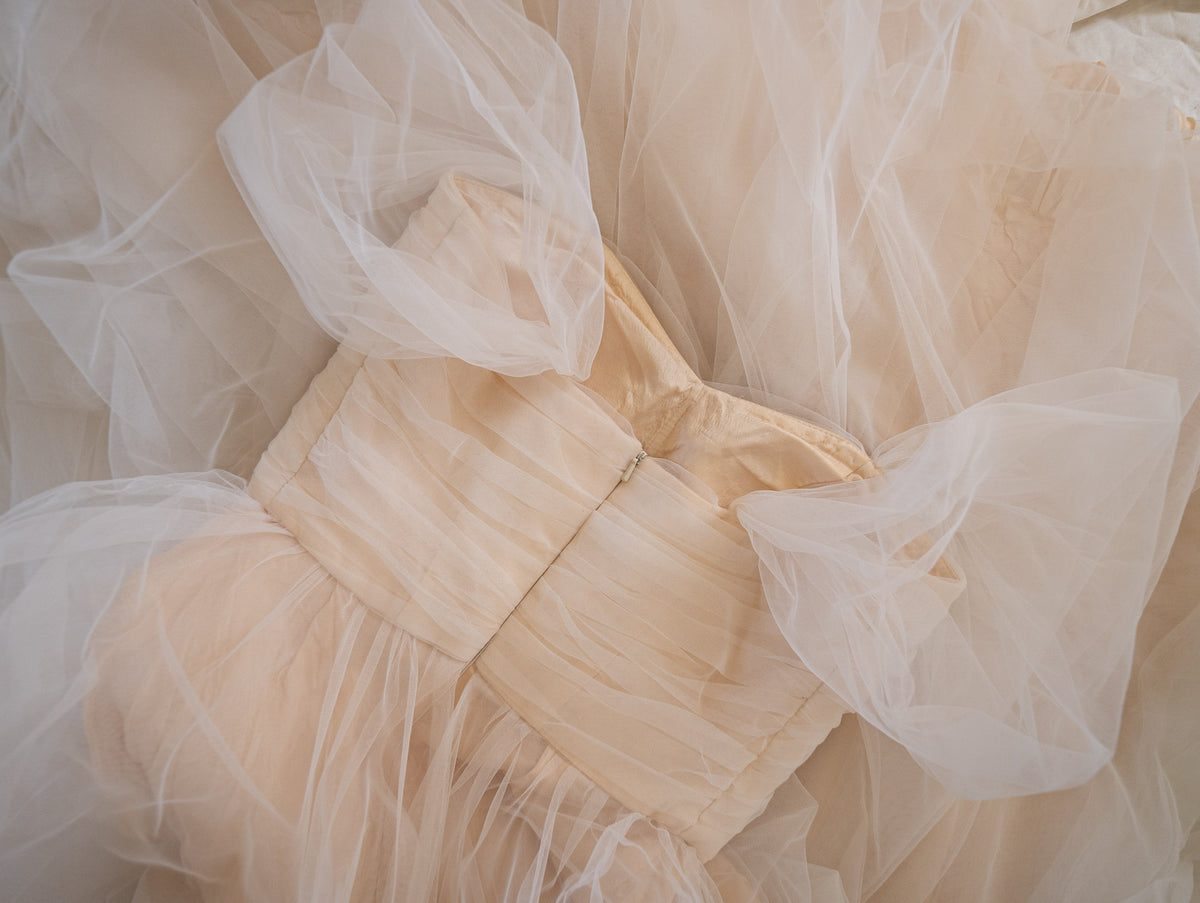 Flat detail of the back of a tulle sample wedding dress, pleated bodice, zip and puff sleeves over the champagne lining, Whisper Sample