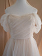 Front close-up of a sample wedding dress on a mannequin, diagonal tulle pleats across the bodice and sheer puff sleeves, Whisper Sample