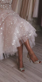 Close crop of a layered tulle midi skirt with stars on a wedding dress, legs crossed in glitter heels, Wild Stars