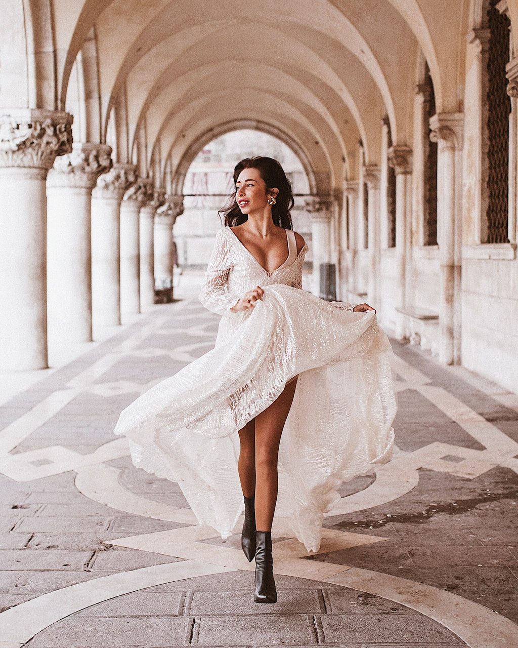 Bride walking through a marble arcade in black boots, ivory lace wedding dress swinging open at the slit, Galaxy Ivory Sample