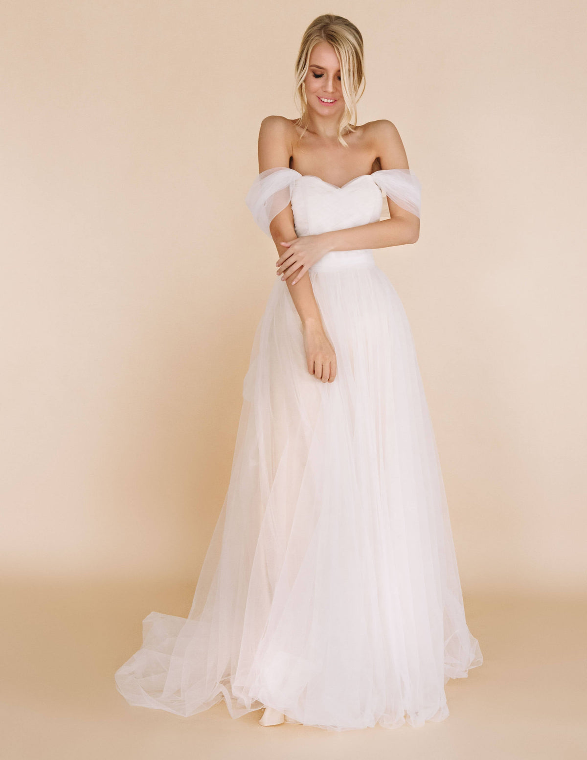 Front view of an off-shoulder tulle sample wedding dress with a sweetheart pleated bodice and soft A-line skirt, beige studio, Whisper Sample