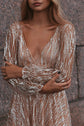 Close crop of the plunging V neckline and cuffed sheer sleeves on a champagne glitter lace wedding dress, arms crossed, Galaxy Champagne