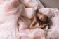 Bride lying in a cloud of blush tulle, wedding dress skirt spread around her, overhead shot, Peony
