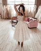 Model posing with an arm raised in a strappy midi star wedding dress, salon rails and a pink sofa behind, mirror selfie, Wild Stars