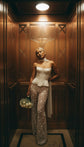 Bride in a satin corset top and star lace wide-leg wedding pants in a wood-panelled hotel lift, scarf and white roses, Galactic Outlaw