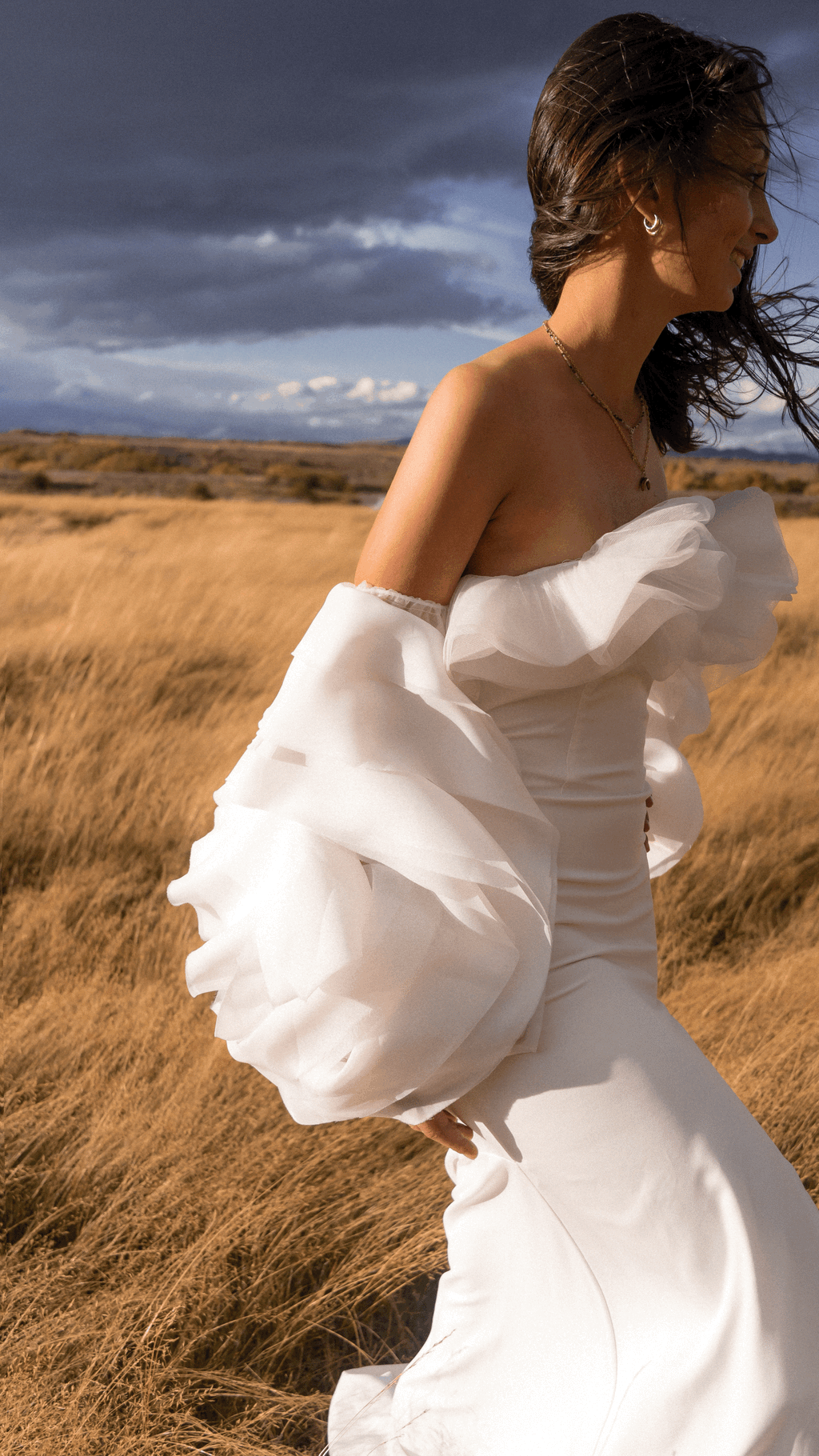 Profile of a bride in a tussock field, oversized organza detachable sleeves billowing in the wind, My Darling Hurricane Sleeves