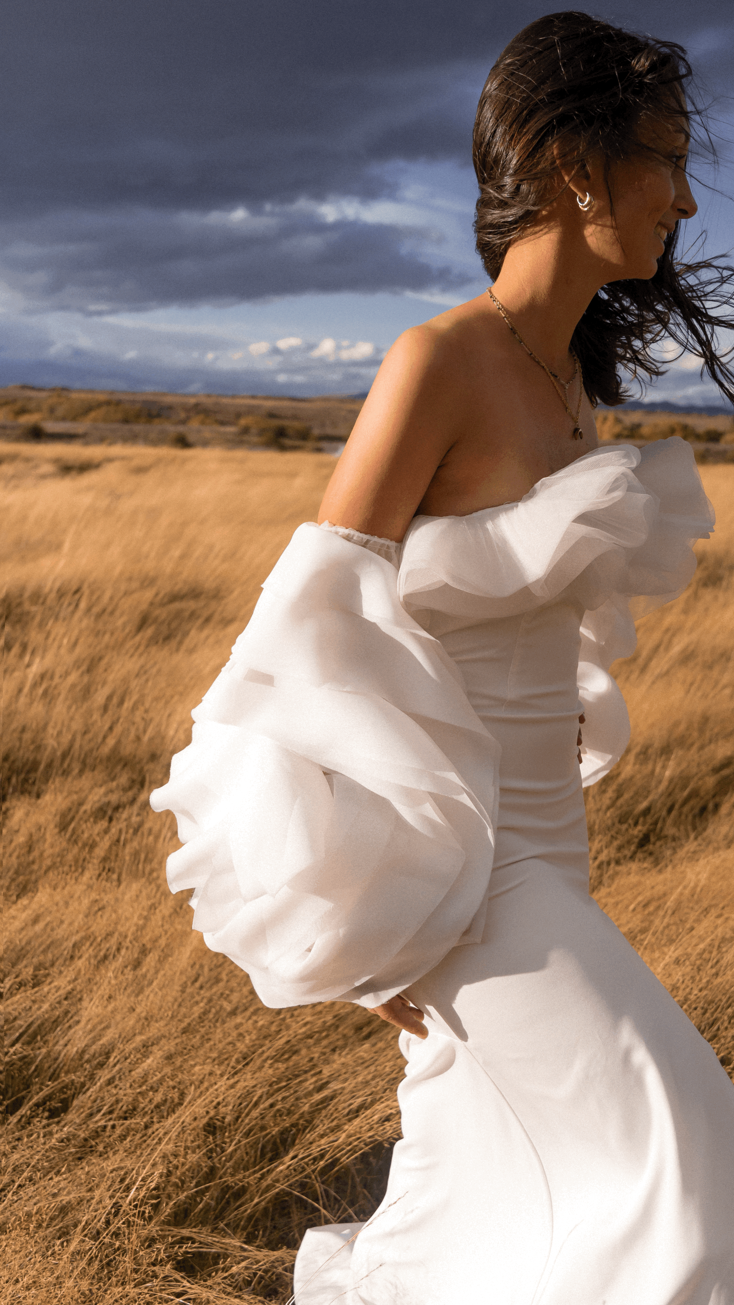 Profile of a bride in a tussock field, oversized organza detachable sleeves billowing in the wind, My Darling Hurricane Sleeves