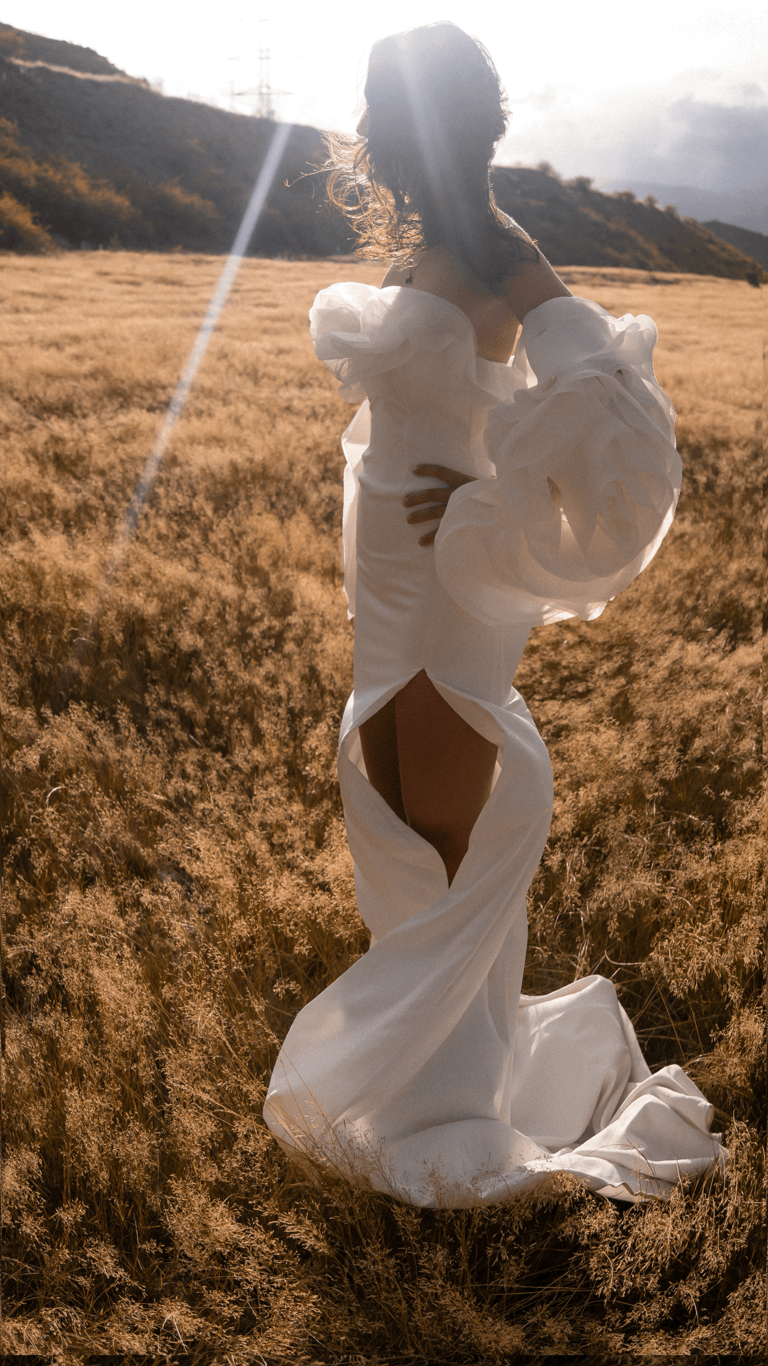 Back view of statement detachable sleeves on a bride in a slit crepe gown with train, sun flare over the hills, My Darling Hurricane Sleeves